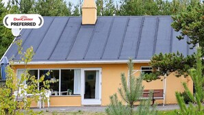 A two-story building with a dark roof and a yellow facade. There is a sign indicating it is a DanCenter Preferred location. - 7 Person Holiday Home in Jerup (Strandby)