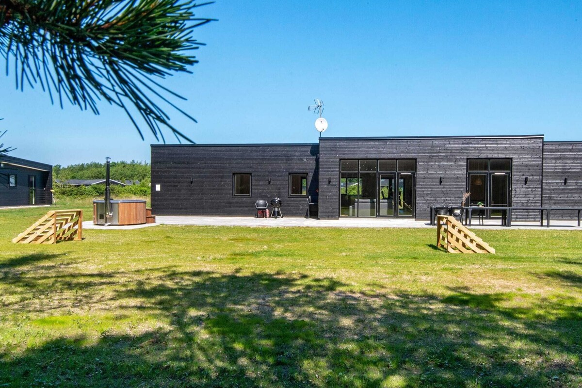 A modern building with a flat roof, large windows, and a patio area with outdoor seating.