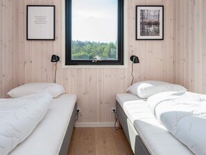 A bedroom with two beds, a window with a view of trees, and two framed pictures on the walls. - 5 Star Holiday Home in Glesborg (Glesborg)