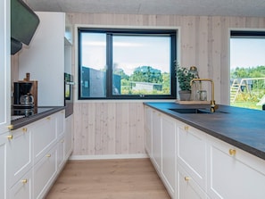 A modern kitchen with a large window, wooden cabinets, and a countertop. - 5 Star Holiday Home in Glesborg (Glesborg)