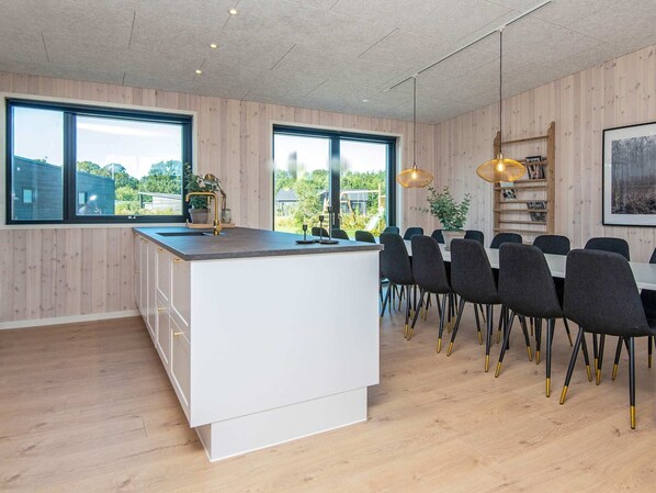 A modern kitchen with a central island, dining area with chairs, and large windows. - 5 Star Holiday Home in Glesborg (Glesborg)