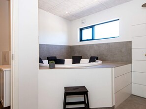 A modern kitchen with a built-in island, a window, and a small stool. - 5 Star Holiday Home in Glesborg (Glesborg)