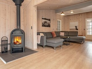 A modern living room with a wood-burning stove, a grey sectional sofa, and a small table with a lamp. - 24 Person Holiday Home in Oster Assels (Øster Assels)
