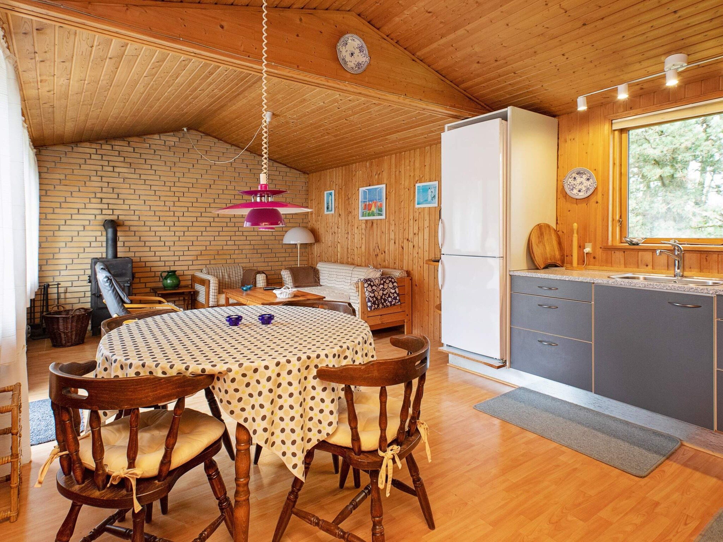 A cozy cabin interior with a dining area, kitchen, and a fireplace.