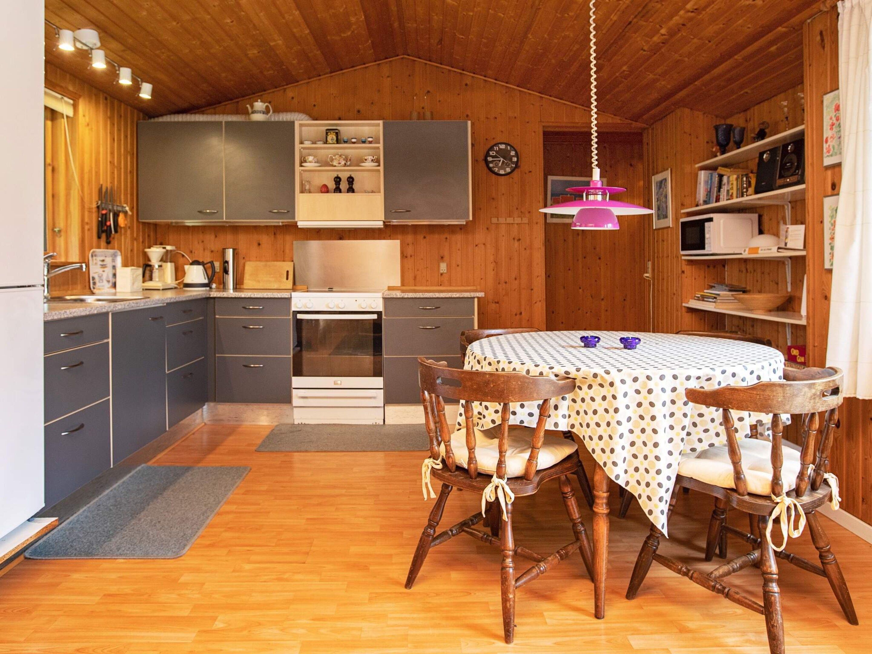A cozy kitchen with wooden cabinets, a stove, and a dining table with chairs.