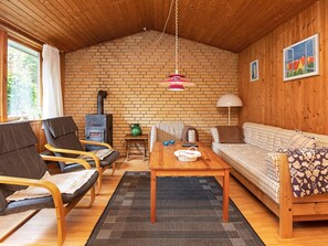 A cozy living room with a brick wall, wooden ceiling, a sofa, a table, and two chairs.