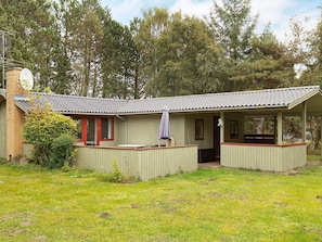 A small, single-story building with a tiled roof, a covered porch, and a small outdoor seating area. - 6 Person Holiday Home in Rodby (Rodby)