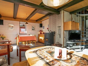 Uma sala de estar acolhedora com lareira, móveis de madeira, um espaço de refeições e uma televisão.