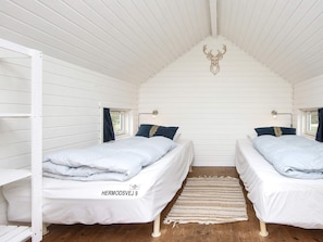 A room with two beds, a ceiling with a deer head decoration, and a window with curtains. - 4 Star Holiday Home in Harboore (Harboore)