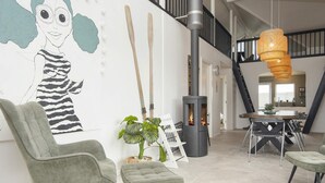 A modern interior with a fireplace, green upholstered chairs, a dining table, and a staircase. - 4 Star Holiday Home in Harboore (Harboore)