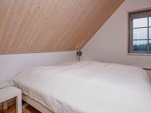 A bedroom with a sloped ceiling, a single bed, a bedside table, and a window with a view. - 5 Star Holiday Home in Laeso (Læsø)