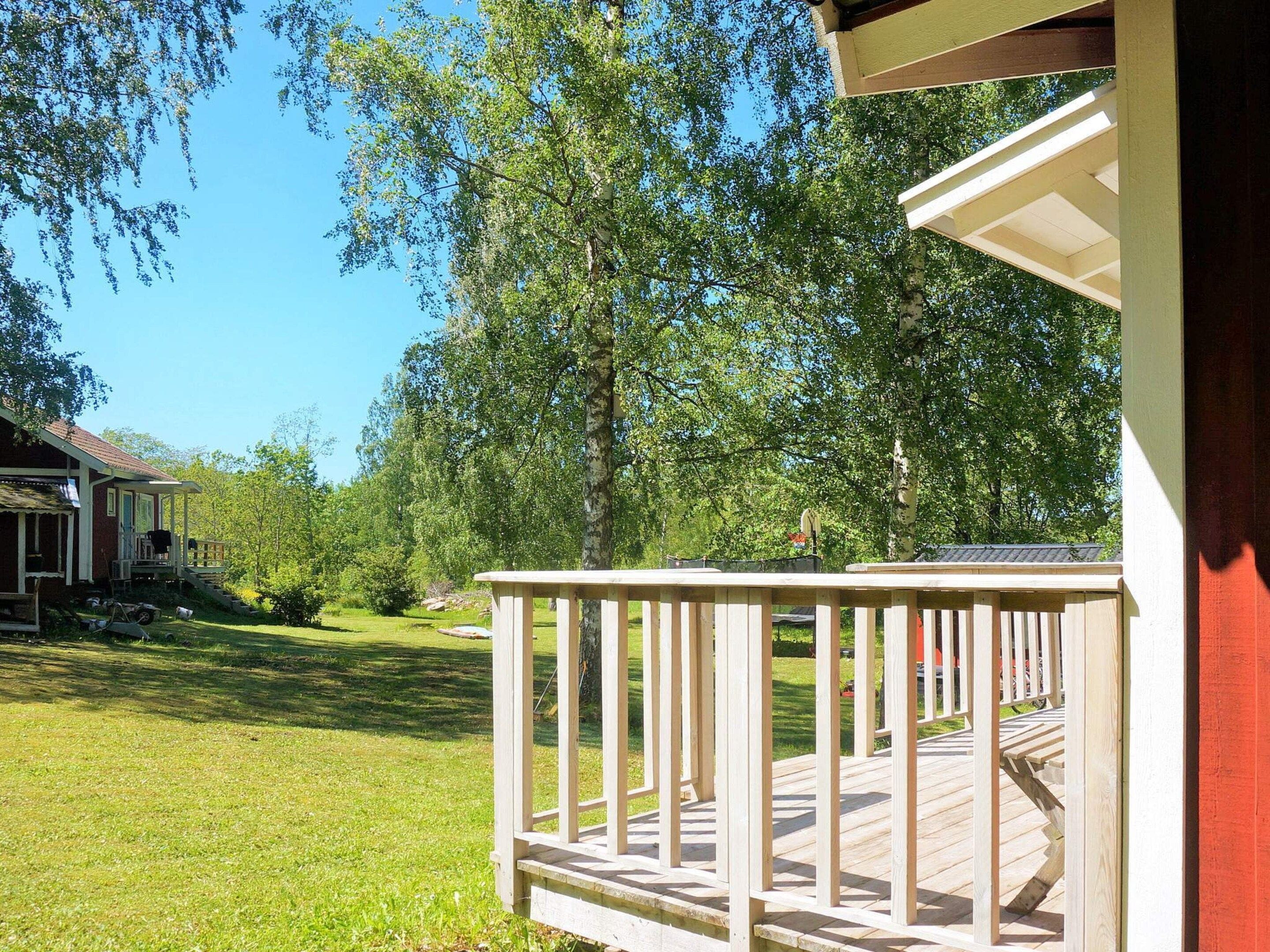 Une terrasse en bois avec une rambarde, une pelouse et une maison en arrière-plan.
