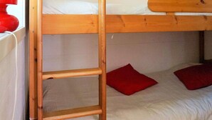 A bunk bed with a wooden ladder, a window with a red curtain, and a white wall. - 4 Person Holiday Home in Axvall (Axvall)
