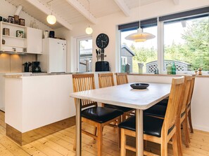 A modern kitchen with wooden chairs, a dining table, and a large window with a view of the outdoors. - 4 Star Holiday Home in Lokken (Lokken)
