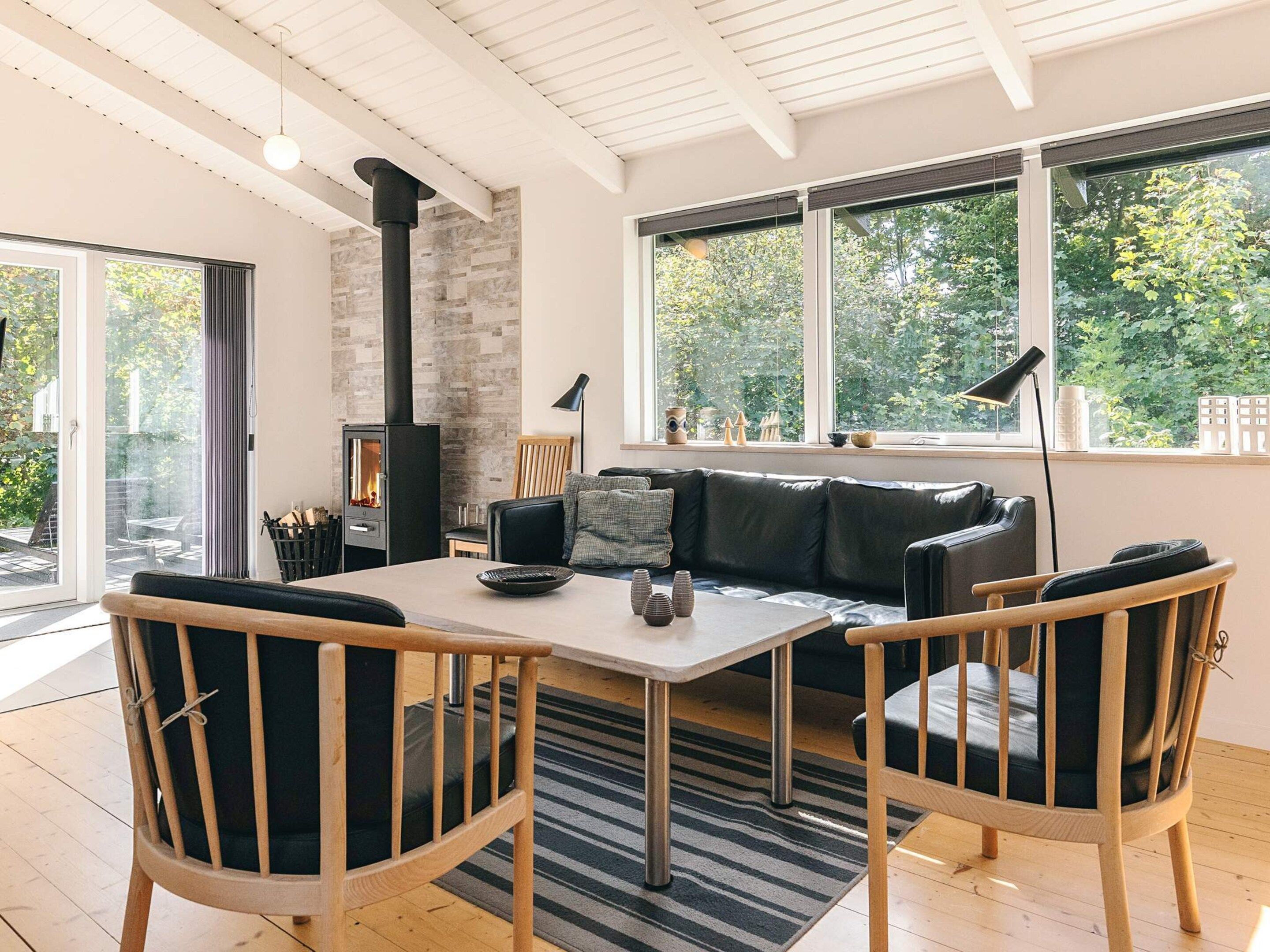 A modern living room with a fireplace, a sofa, a dining table, and chairs.