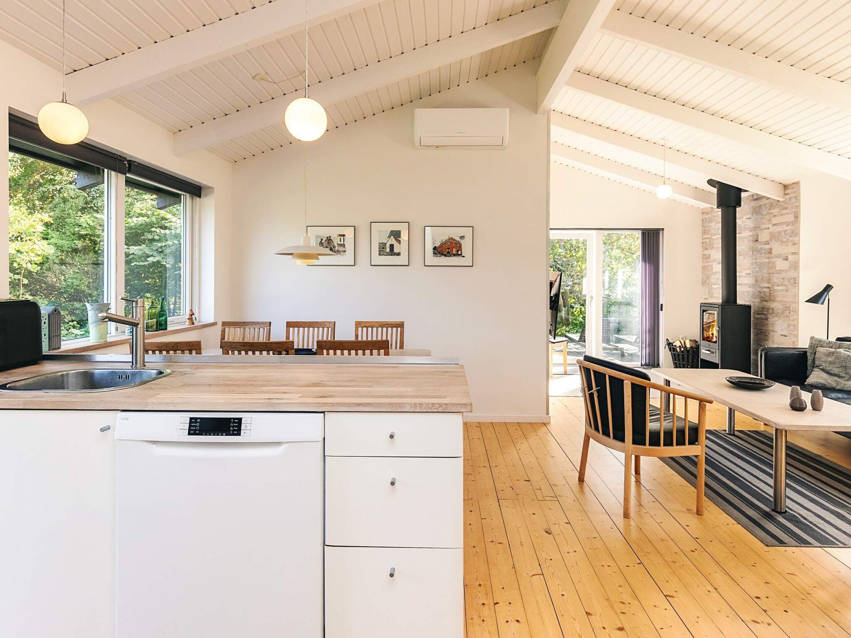 Una cucina moderna con lavastoviglie integrata, tavolo da pranzo in legno e sedie, con una grande finestra che offre vista sull'esterno.