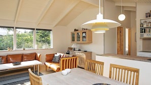 Une cuisine moderne avec des meubles en bois, une table à manger et une grande fenêtre donnant sur un paysage verdoyant.