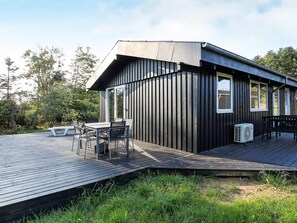 A modern cabin with a deck, a table with chairs, and a bench. - 4 Star Holiday Home in Lokken (Lokken)