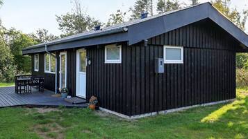 A black metal building with a deck, a door, and windows.