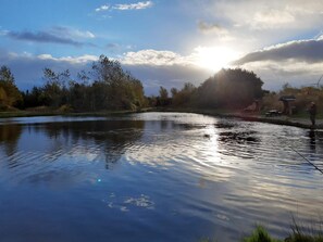 A calm river with trees and a small building in the background. - 5 Star Holiday Home in Ringkobing (Ringkobing)