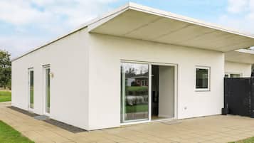 A modern single-story building with a flat roof, large sliding glass doors, and a covered patio area.
