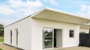 A modern single-story building with a flat roof, large sliding glass doors, and a small window. - 5 Star Holiday Home in Ringkobing (Ringkobing)