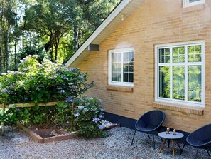 A brick building with a window and a garden area with plants and chairs. - 5 Star Holiday Home in Hadsund (Hadsund)