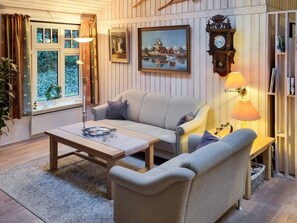 A cozy living room with a sofa, a coffee table, a lamp, a clock, and a bookshelf.