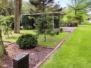 A garden with a wooden bench, a pergola, and a small shed.