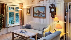 A cozy living room with a sofa, a coffee table, a lamp, a clock, and a bookshelf. - 5 Star Holiday Home in Hadsund (Hadsund)