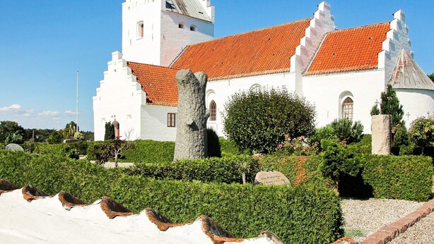 A white building with a red-tiled roof, a stone tower, and a well-maintained garden. - 5 Star Holiday Home in Hadsund (Hadsund)