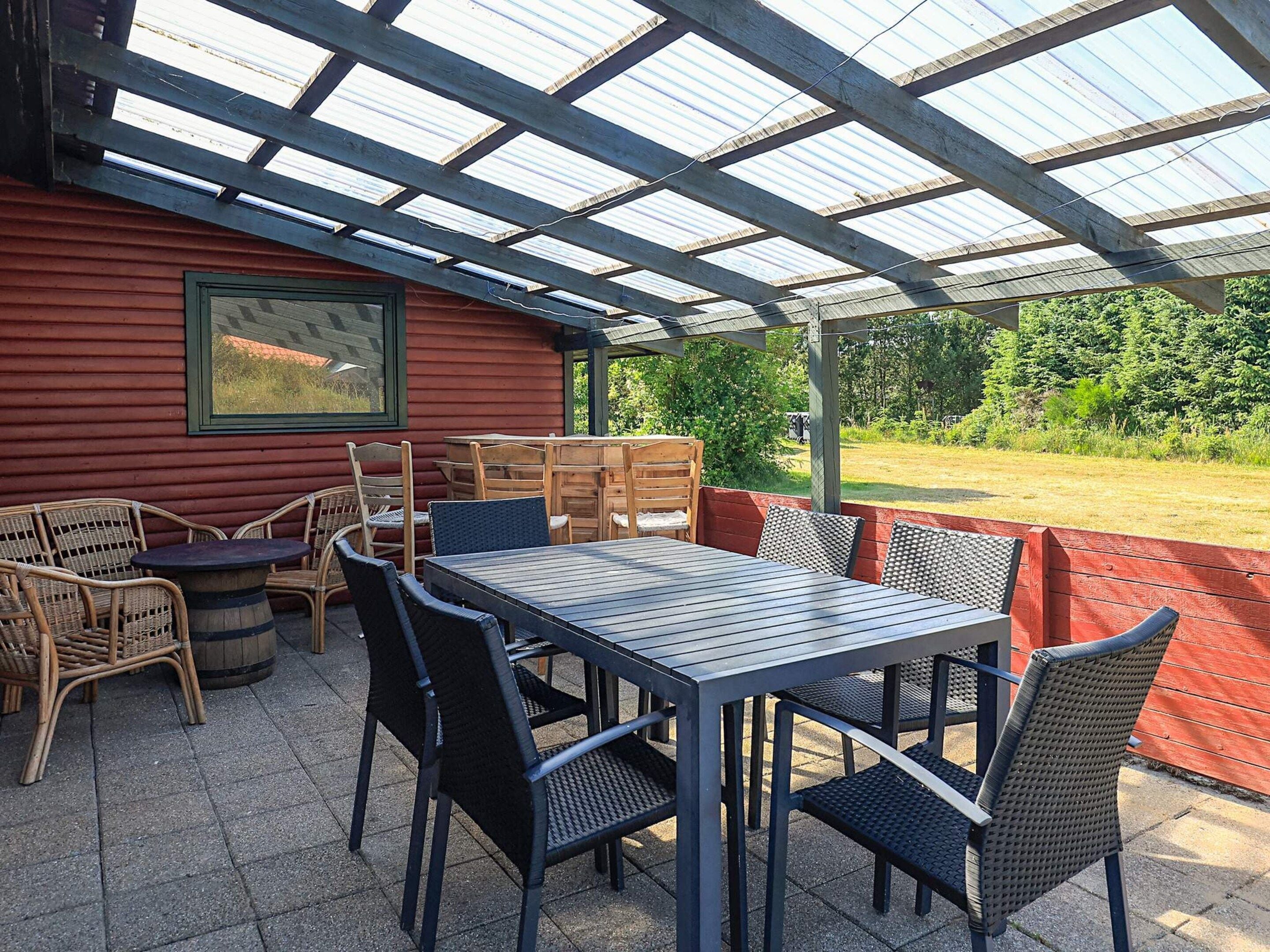 Eine überdachte Terrasse mit Sitzgelegenheit, Tisch und Stühlen.