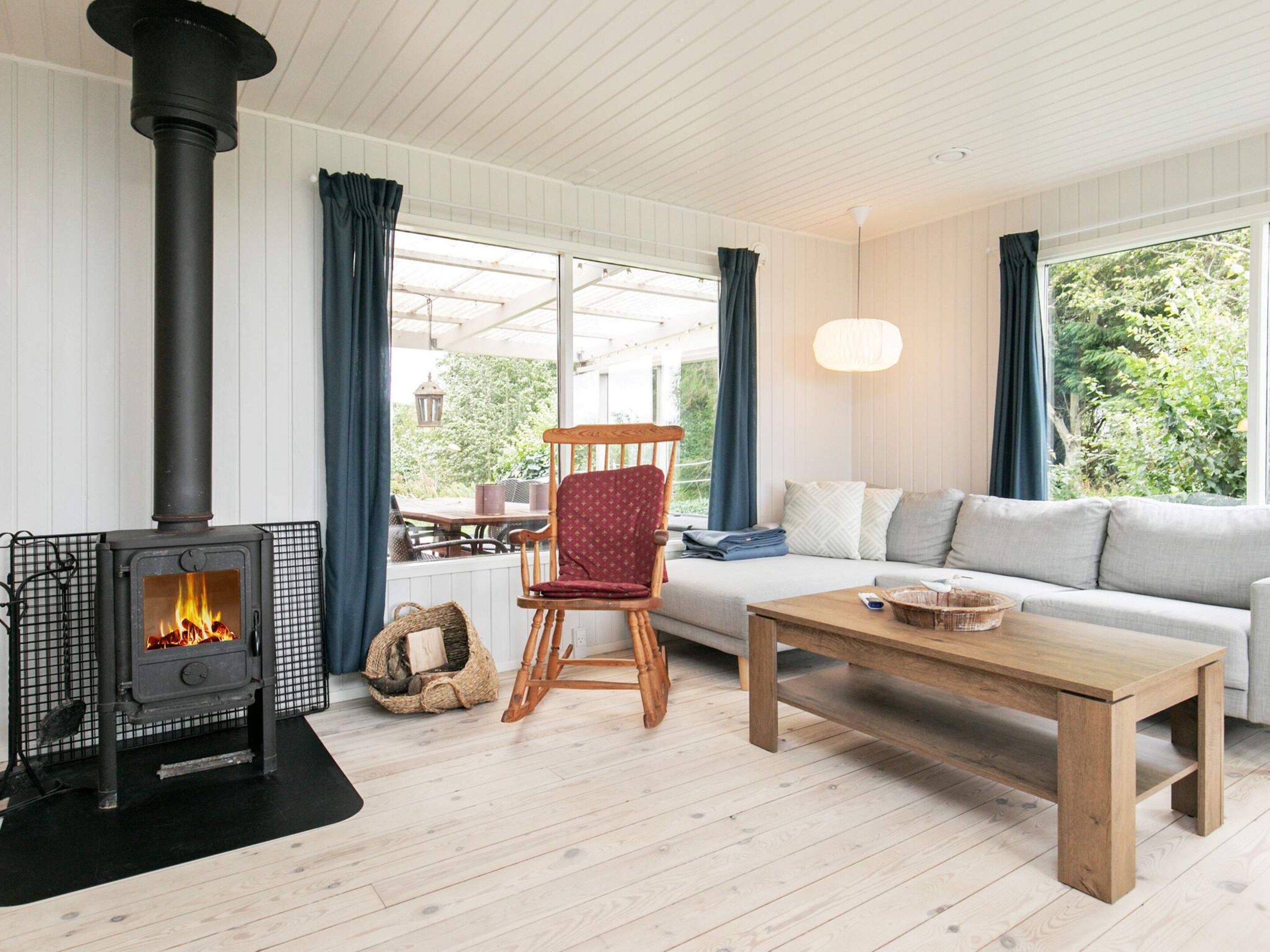 Un salon chaleureux avec un poêle à bois, un canapé, un fauteuil et une table basse.
