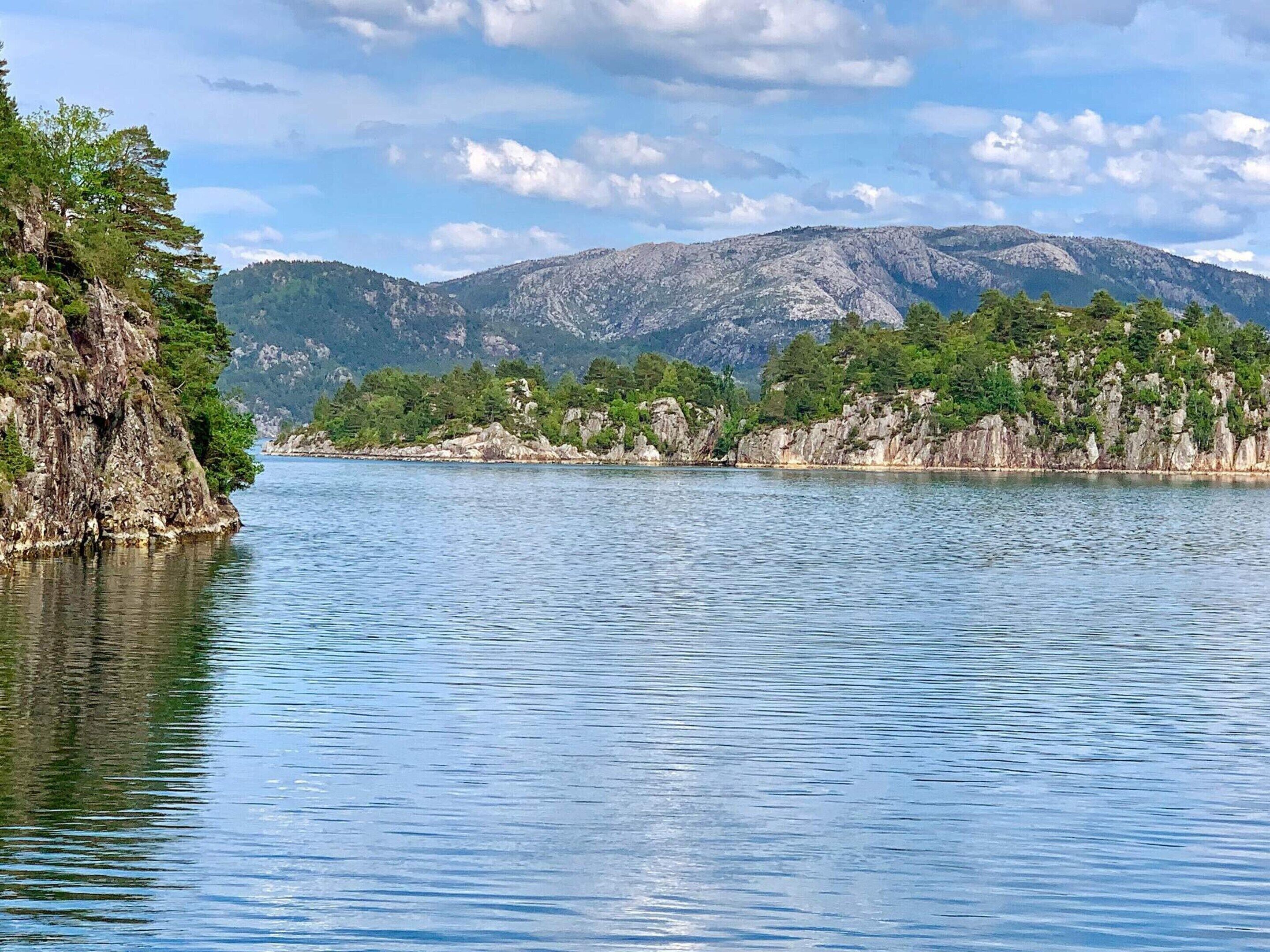 A calm lake with rocky shores and mountains in the background.