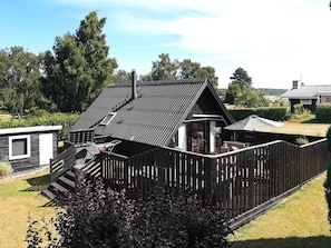 En boligejendom med et hegnede område, en mindre bygning med skråtag og en trappe, der fører op til en etage.