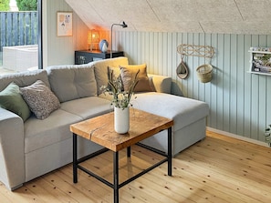 En moderne stue med en modulsofa, et træsofabord og en vase med tørrede planter.
