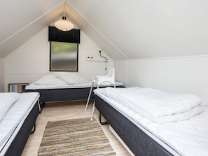A dormitory room with two beds, a desk, a chair, a lamp, and a window with blinds. - 4 Star Holiday Home in Hejls (Hejls)