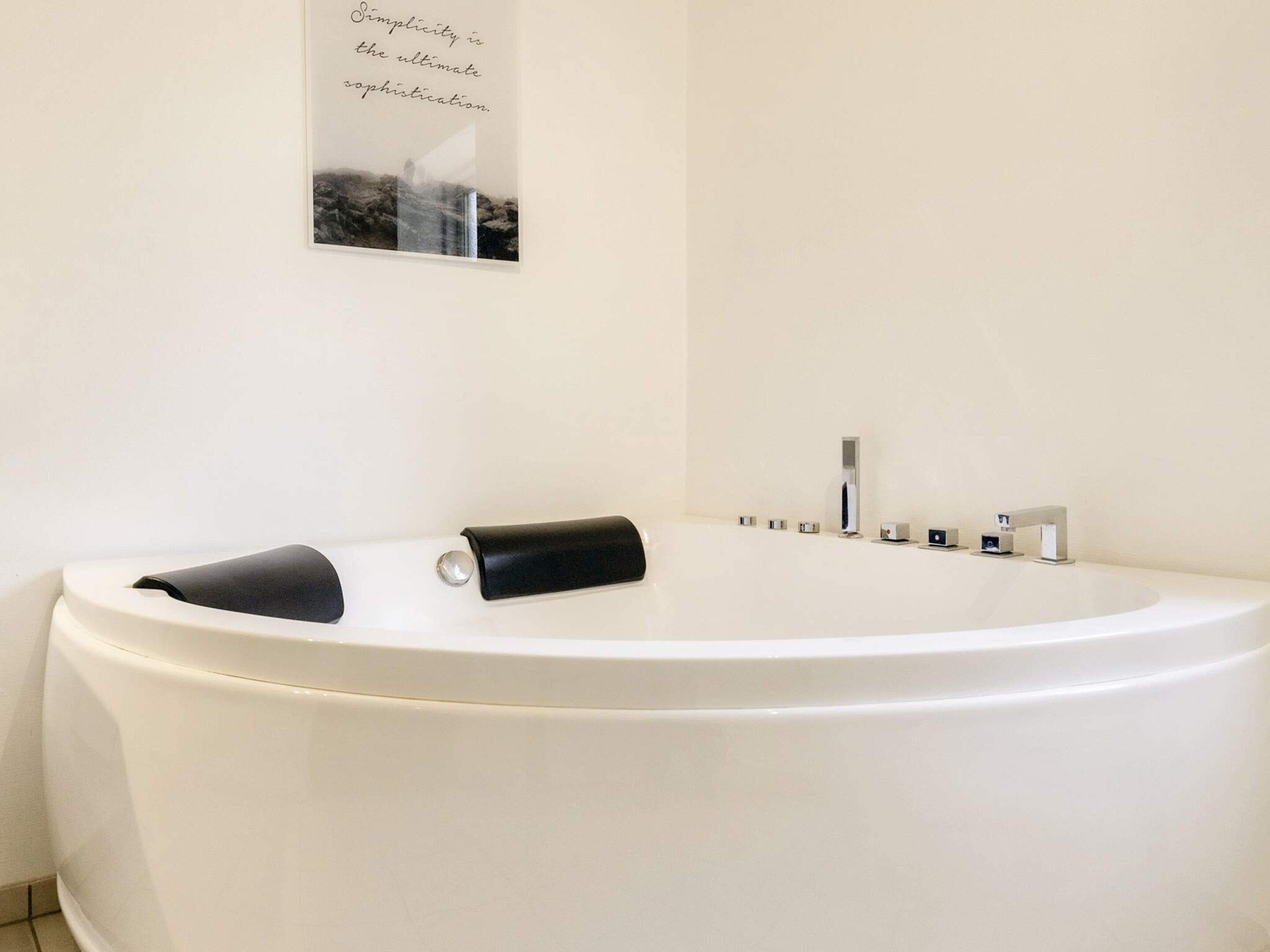 Un bagno moderno con una vasca autonoma, uno specchio fissato alla parete e un porta asciugamani.