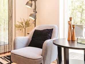 A modern armchair with a black cushion, a round table with wooden salt and pepper shakers, and a floor lamp. - 5 Star Holiday Home in Hadsund (Hadsund)
