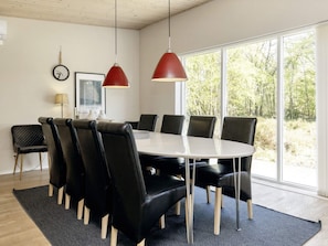 A conference room with a round table, black chairs, and red pendant lights.