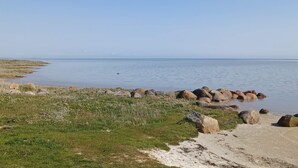 A coastal landscape with a clear sky, a sandy beach, and scattered rocks. - 5 Star Holiday Home in Hadsund (Hadsund)