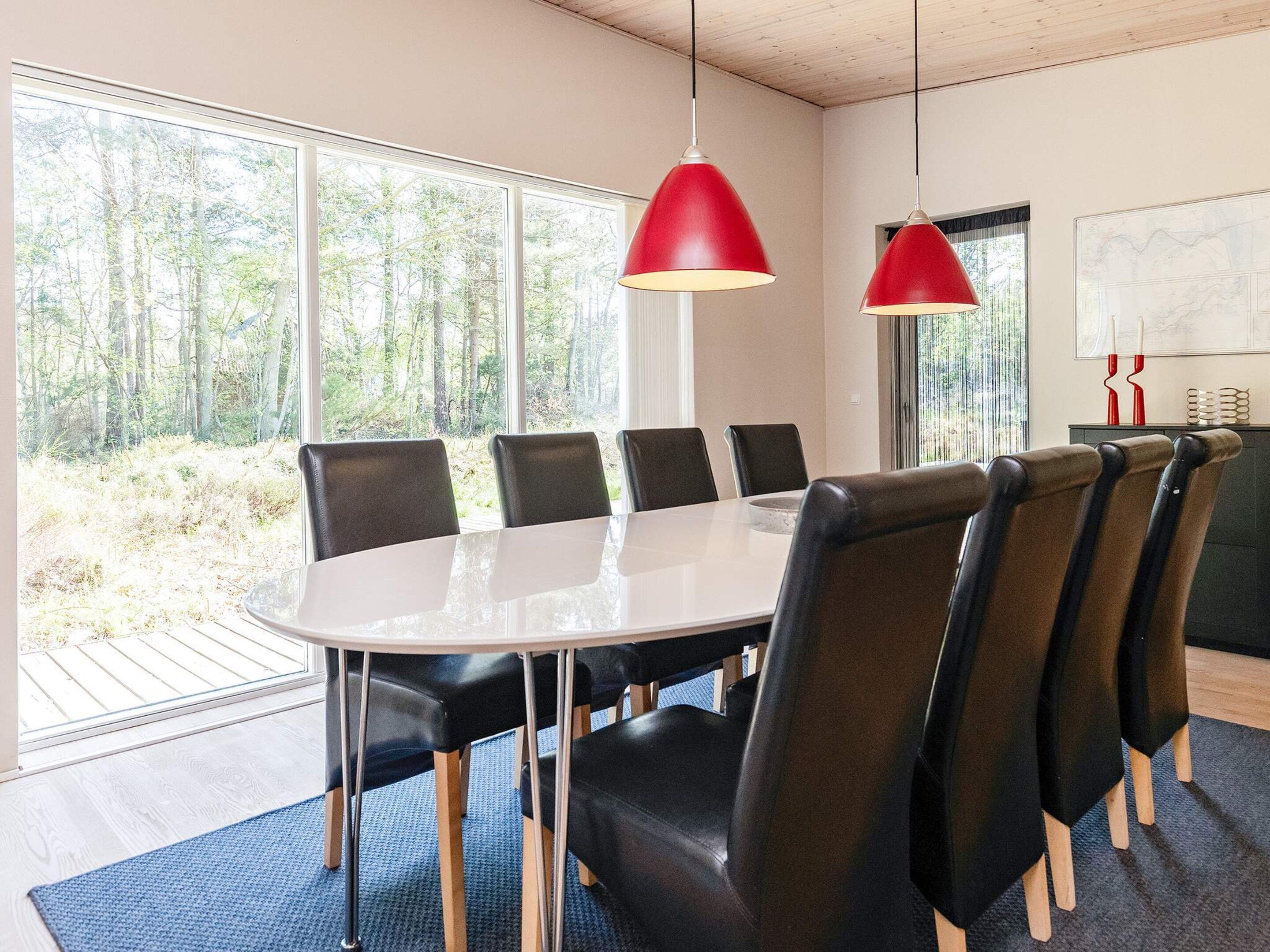 A conference room with a round table, black chairs, and red pendant lights.