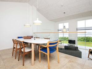 Uma sala de jantar moderna com uma mesa redonda, cadeiras de madeira e iluminação pendente.