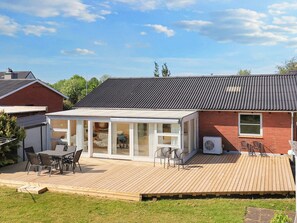 A house with a covered patio, a dining area with chairs, and a red brick exterior. - 5 Person Holiday Home in Albaek (Aalbaek)