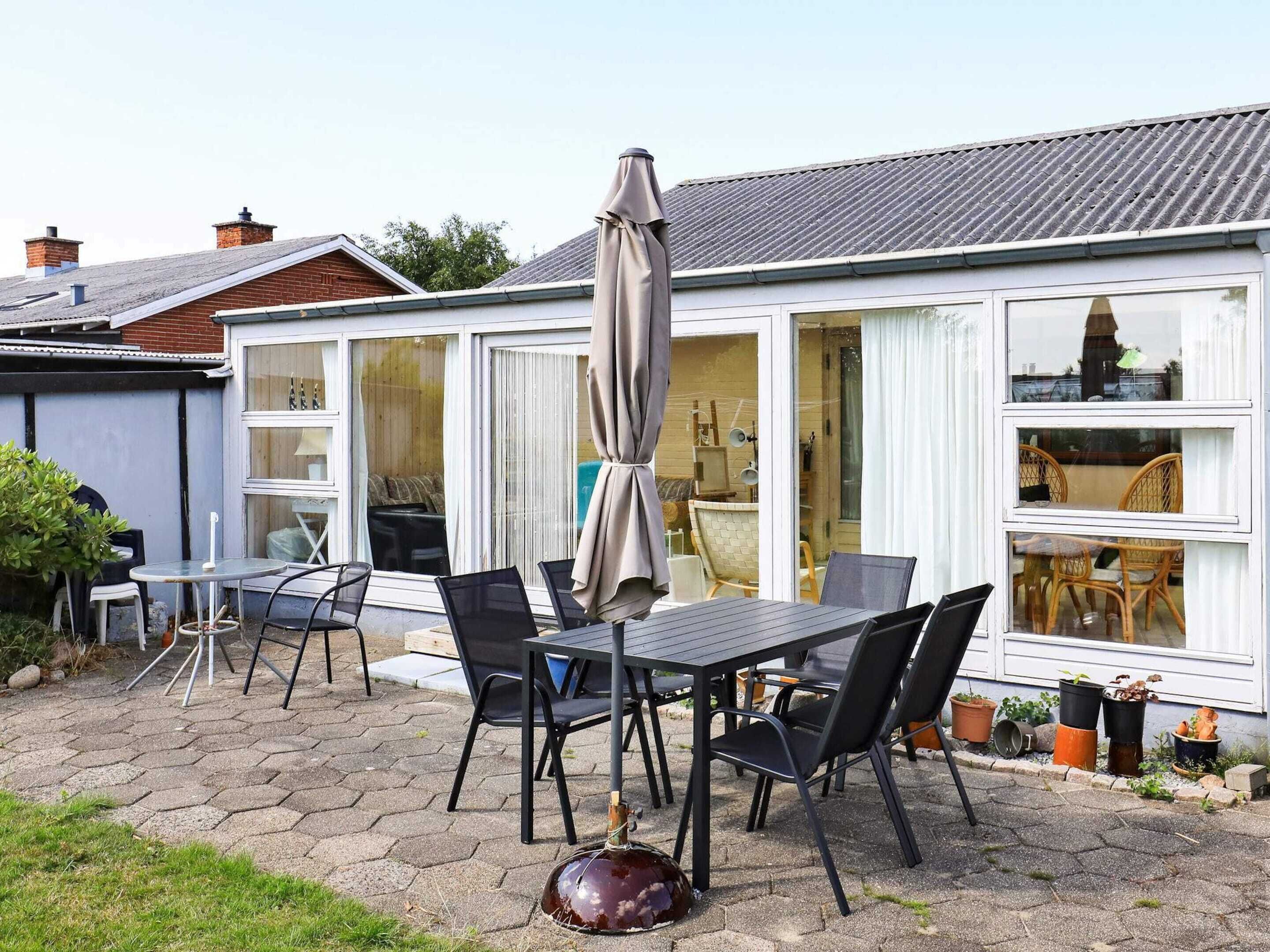 A patio with a table and chairs, a large umbrella, and potted plants.