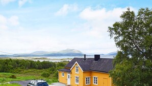 A yellow house with a paved driveway and a parked car. - 7 Person Holiday Home in Skutvik (Hamaroy)