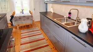 A kitchen with a wooden table, striped rug, and a coffee maker. - 7 Person Holiday Home in Skutvik (Hamaroy)