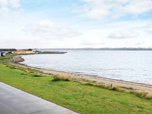 A coastal road with a grassy area and a body of water. - 10 Person Holiday Home in Farso (Farso)