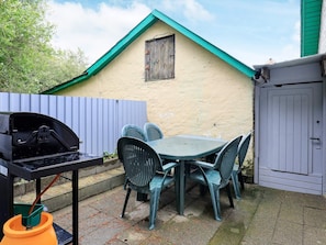 A patio with a grill, table, chairs, and a small building with a window. - 10 Person Holiday Home in Farso (Farso)