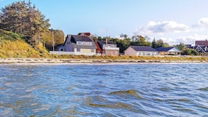 Een kustbezit met meerdere huizen aan een zandstrand, zichtbaar door helder water.